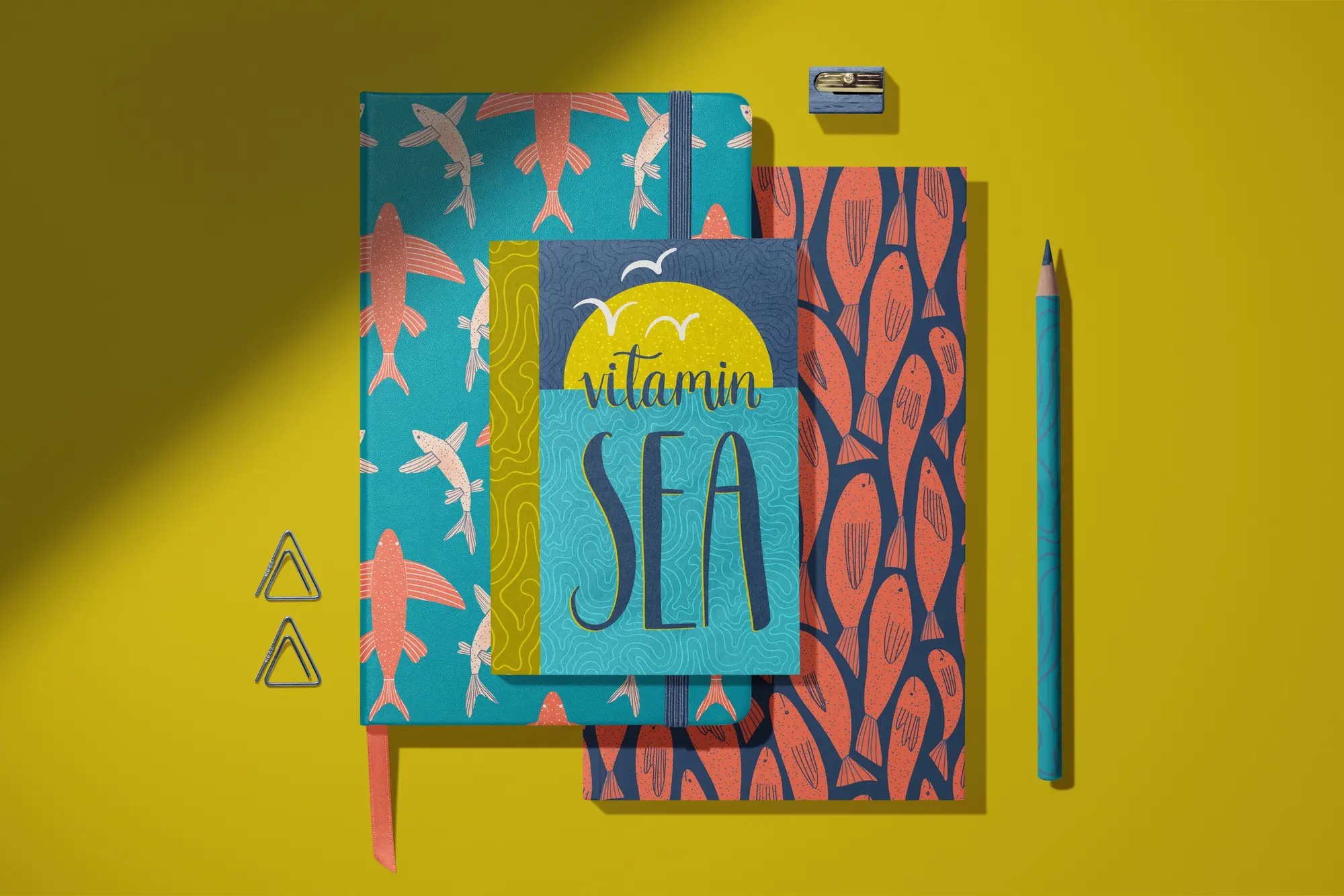 Vitamin Sea notebooks with flying fish and coral fish patterns on a yellow desk